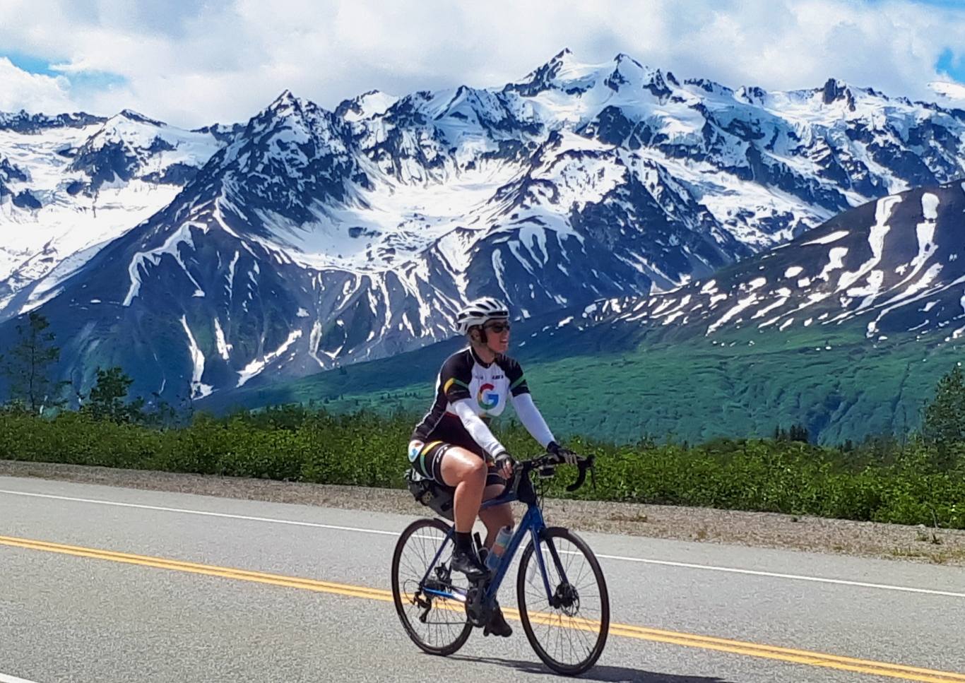 Bicyclist passing snow capped mountains