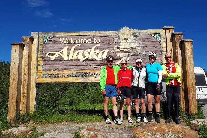 bicyclists at welcome to Alaska sign