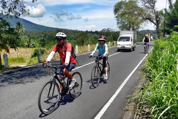 cyclists riding along rural road Bali