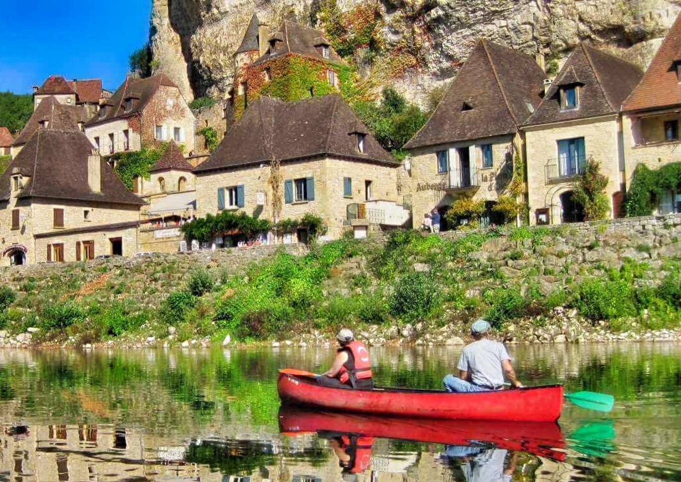 Canoeists passing french village on Dordogne Rver