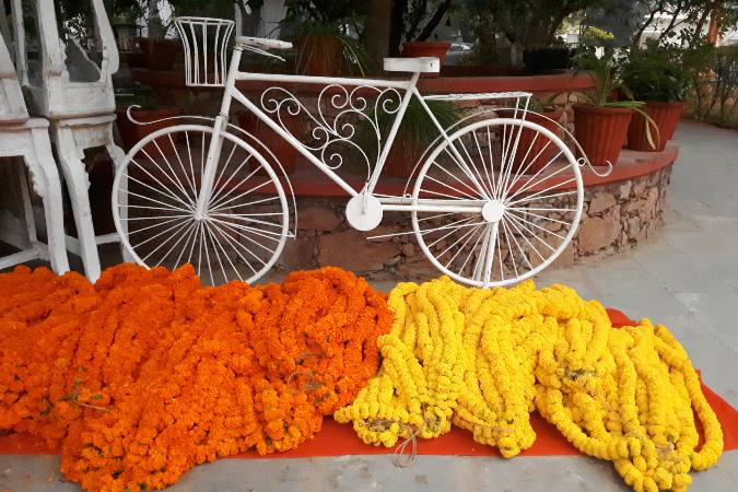 orange and yellow wedding garlands by bicycle sculpture
