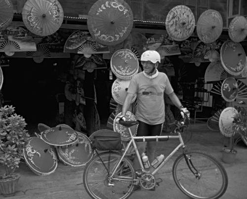 cyclist riding past umbrella shop in Bo Sang