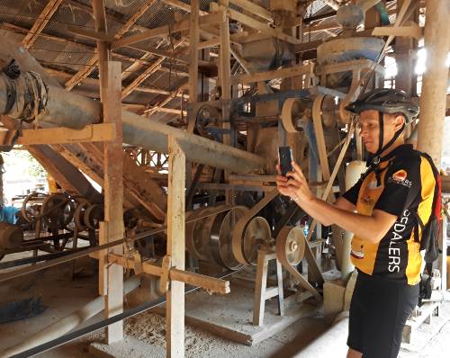 a Pedalers guest observing a historic rice husking machine